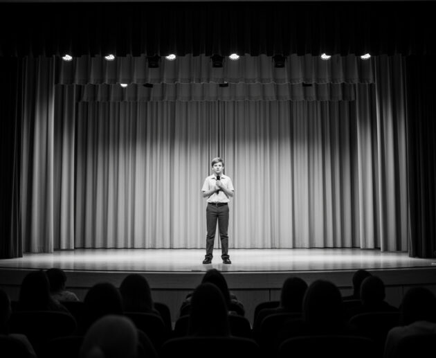 A shy student performing on stage during a school competition